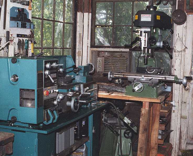 Machinery in cluttered workshop setting with blue lathe and green drill press.