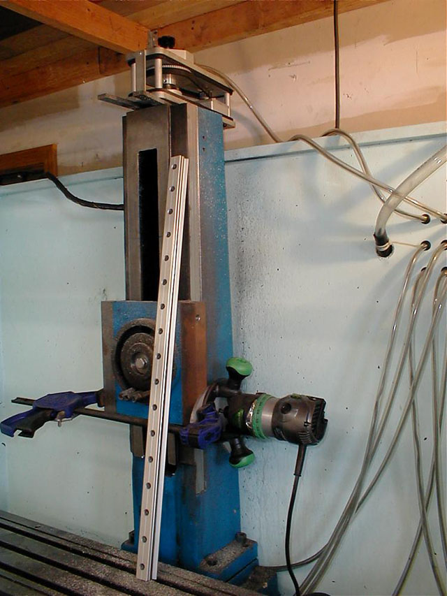Metal machine with vertical column and rotating wheel in workshop setting.