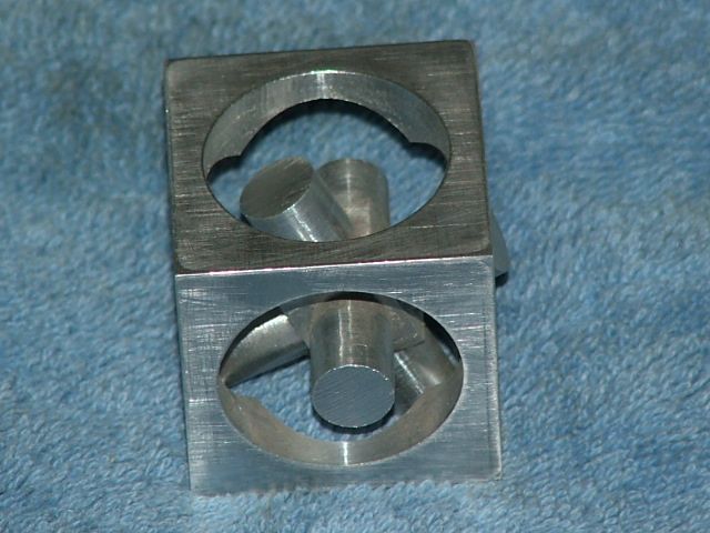 Two square metal pieces with circular holes on a blue surface, both with brushed aluminum finish.