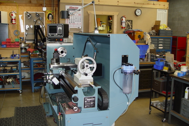 A large blue metal lathe in a workshop or machine shop.
