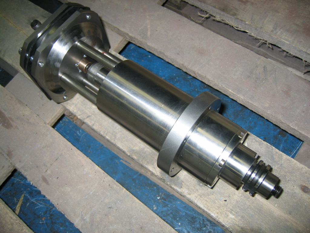 Cylindrical metal component with central shaft and attached machinery.