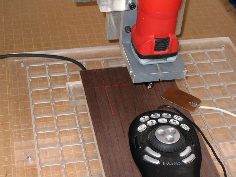 Red router cutting wood cross on laser mount.