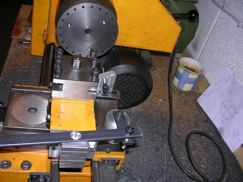 Yellow lathe slotter machine on a workbench in a well-lit workshop.