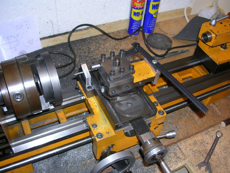 Yellow and black lathe with tools and parts on its surface, and metal components visible inside.