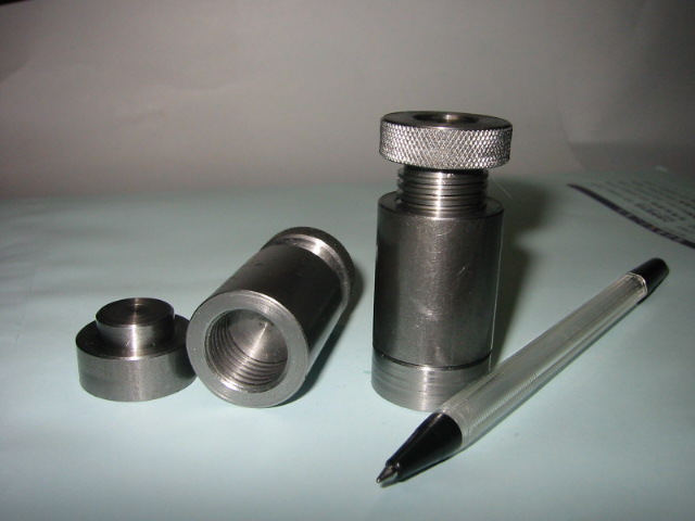 Metal parts with a ballpoint pen on a white surface.