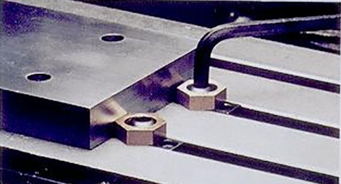 Eccentric clamp with hexagonal nut on flat surface.