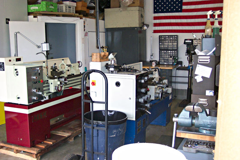 Cluttered workshop with red and white metal lathe, metalworking equipment.