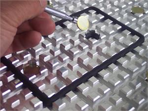 Hand holding magnifying glass over precision grid table.