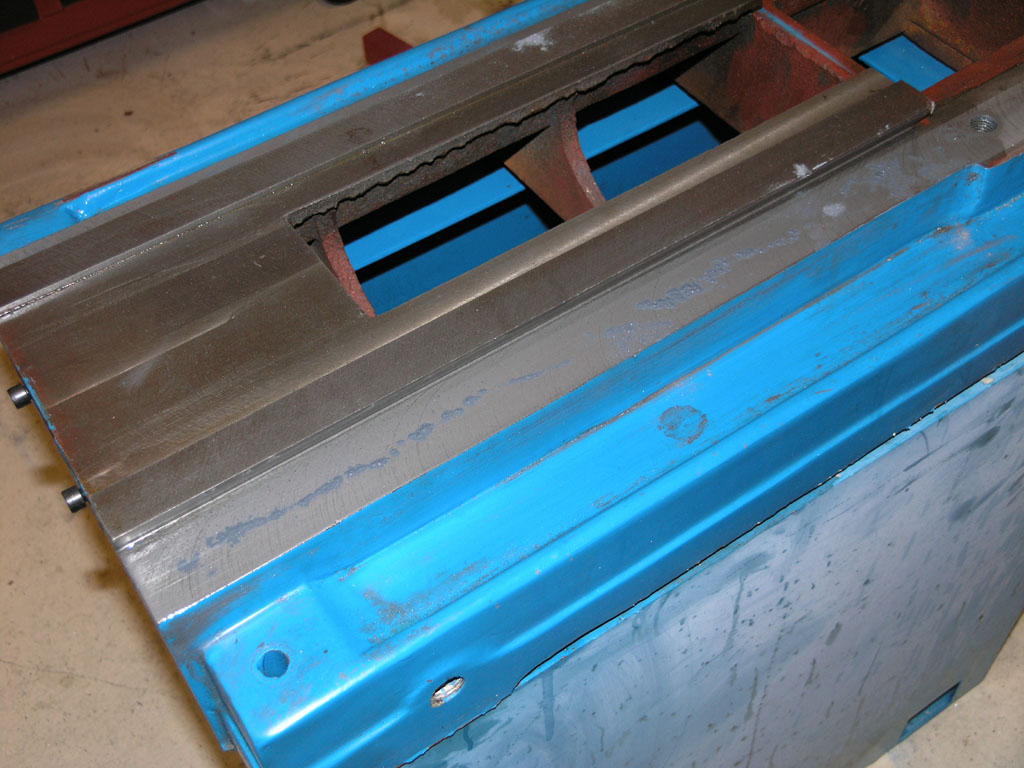 Industrial metal component, blue-painted, rectangular holes and slots.