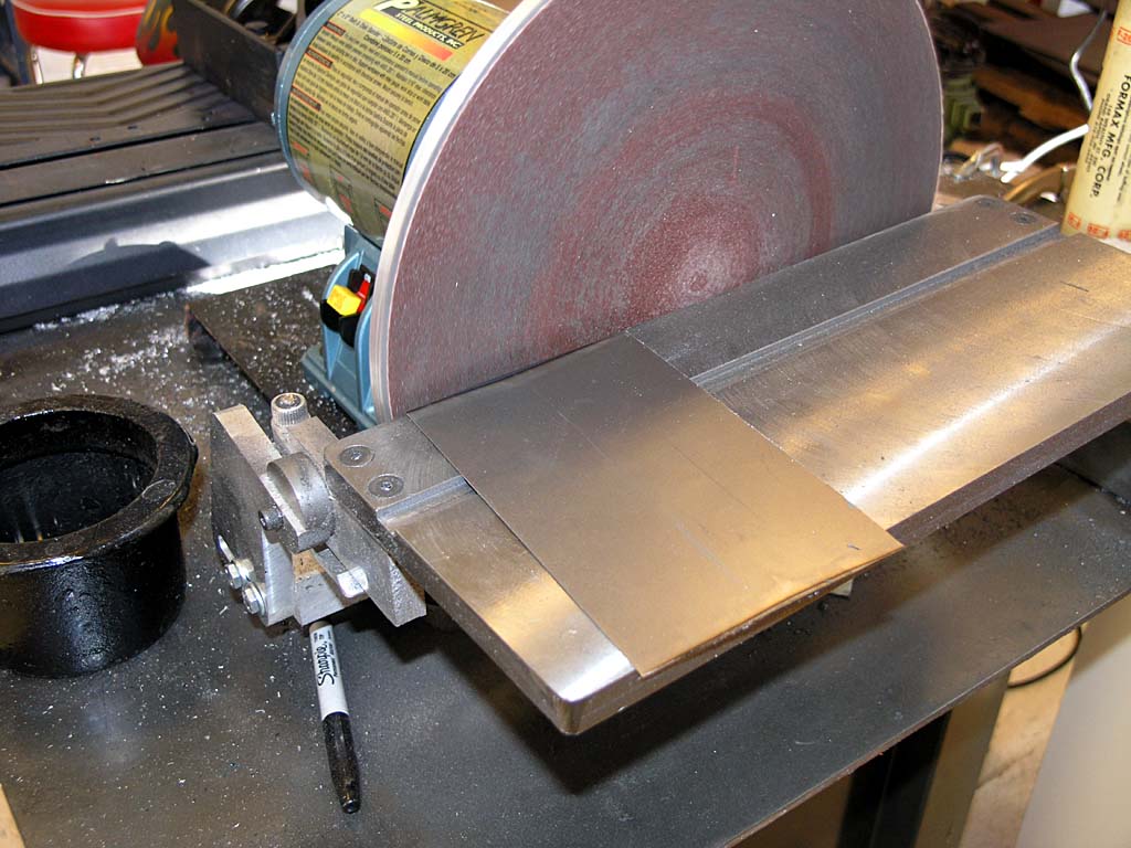 Metalworking bench grinder with black base and silver metal components featuring a large round stone wheel.