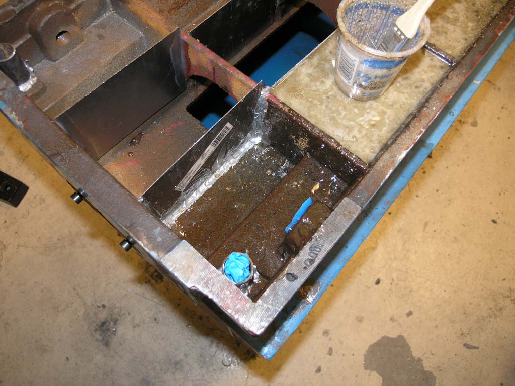 Metal frame with tools and materials scattered on a concrete floor.
