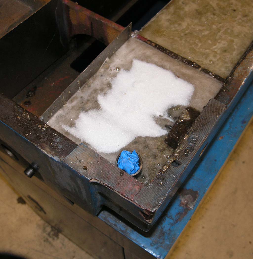 Metal box in workshop setting with white powder on top, likely salt or sugar.