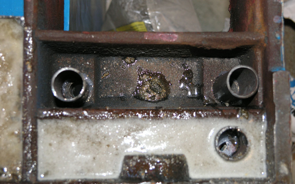 Rusty metal frame with bolts and screws on a neutral background.