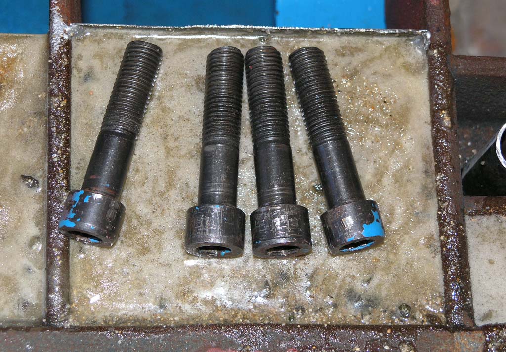 Black bolts on dirty concrete, possibly related to machining or metal fabrication.