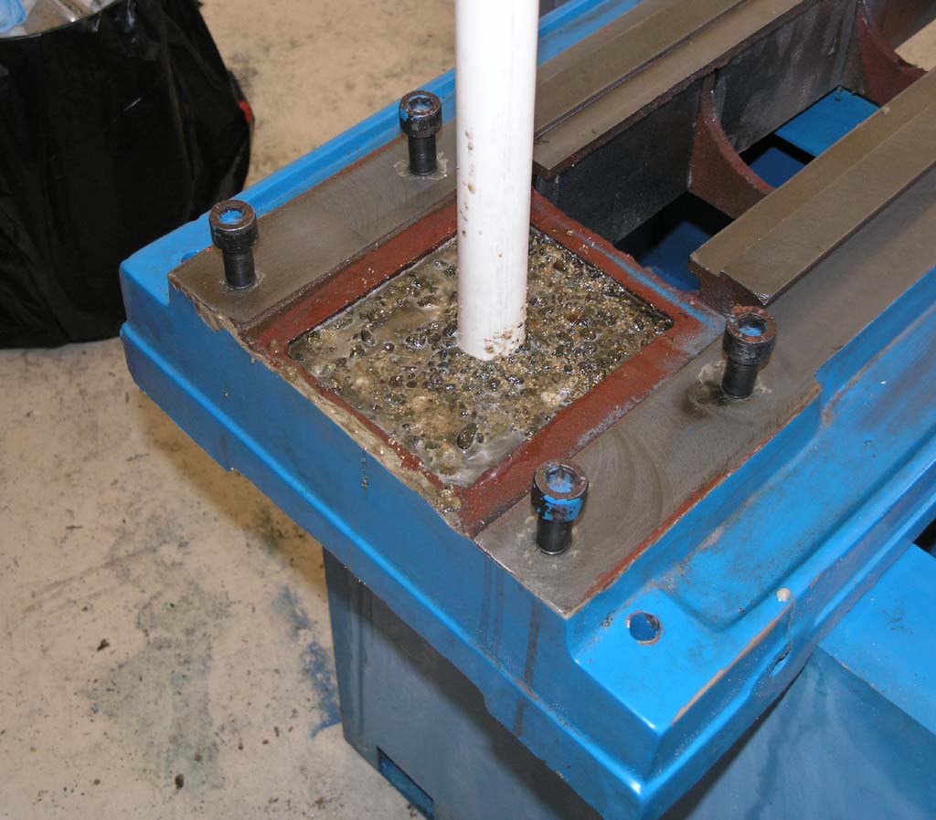 Blue metal object on concrete floor, white pole protruding from center, red border.