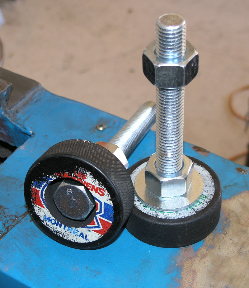 Two hockey pucks: Montreal Canadiens logoed and unlogoed, on a workbench with two bolts.