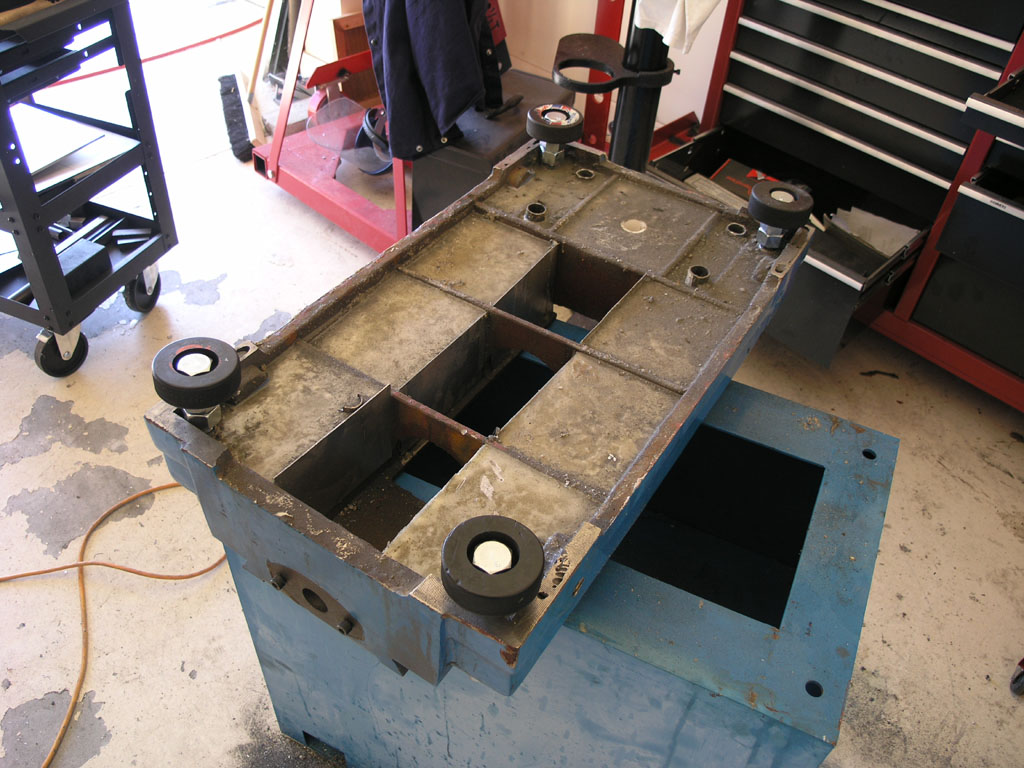 Industrial metal machine base on blue box in workshop setting.