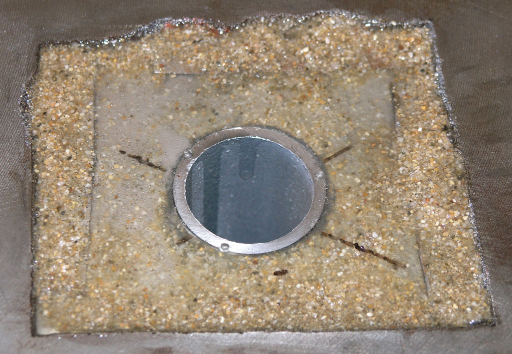 Square concrete patch with a circular metal insert.