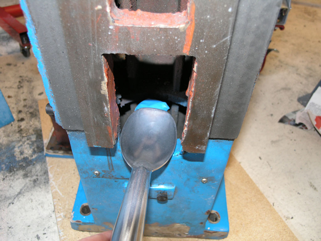 Metal working setup with blue base and metal object on a concrete workshop floor.