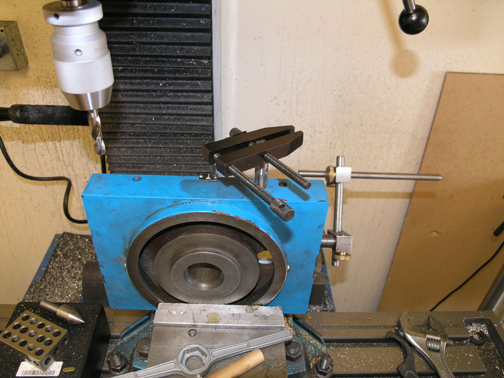 A blue metalworking lathe with various tools and machinery components in a well-equipped machine shop or workshop setting.