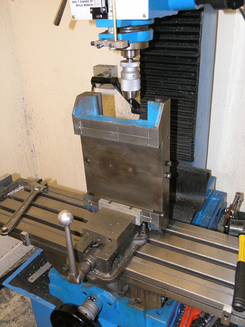 Milling machine with various tools and parts on a large metal base with rotating head and accessories.
