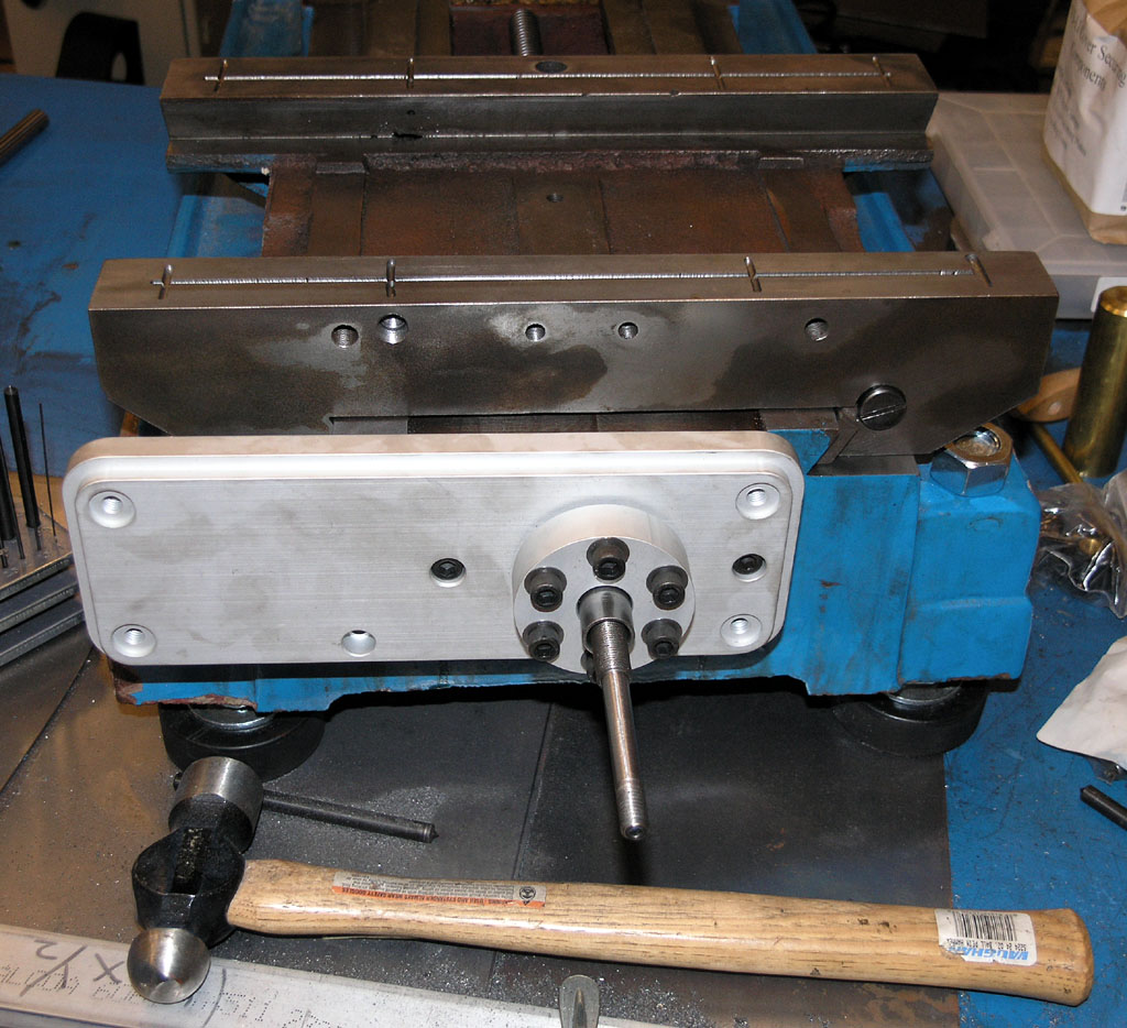 Heavy-duty metalworking vise on workbench with tools and machinery parts in the background.