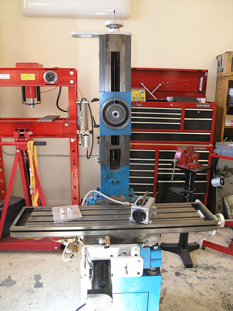Well-equipped workshop with machinery and tools, including a red metal press, blue lathe, and black grinder.