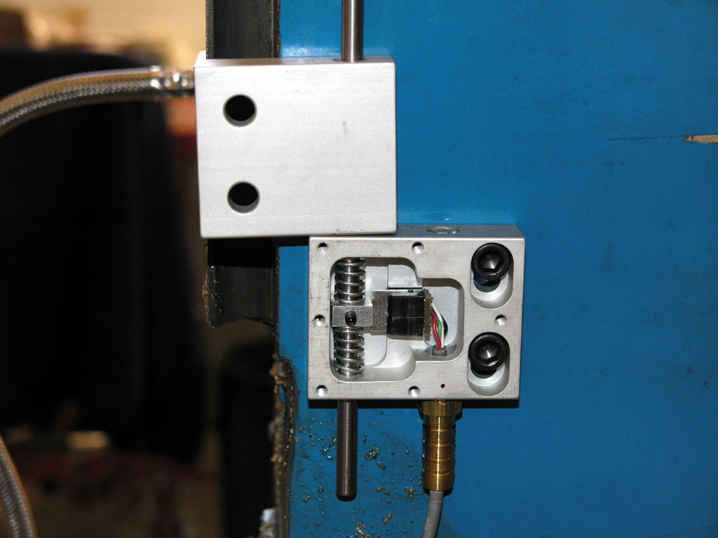 Metal device in machine shop setting with metal base, rectangular blocks, springs, wire, and brass rod.