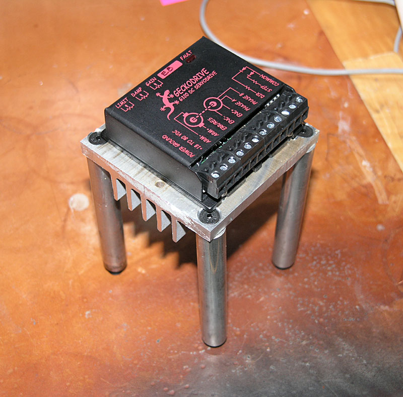 Small black electronic device with red text and symbols on metal stand.