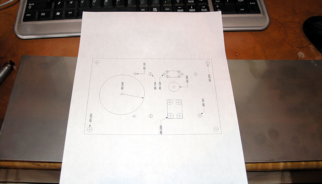 Technical drawing on white paper on a silver surface next to a black keyboard.
