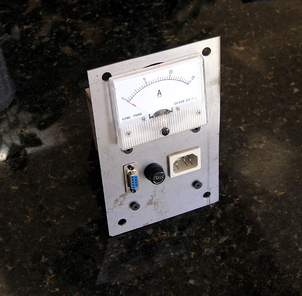 Old analog ammeter with dial gauge and industrial setting.