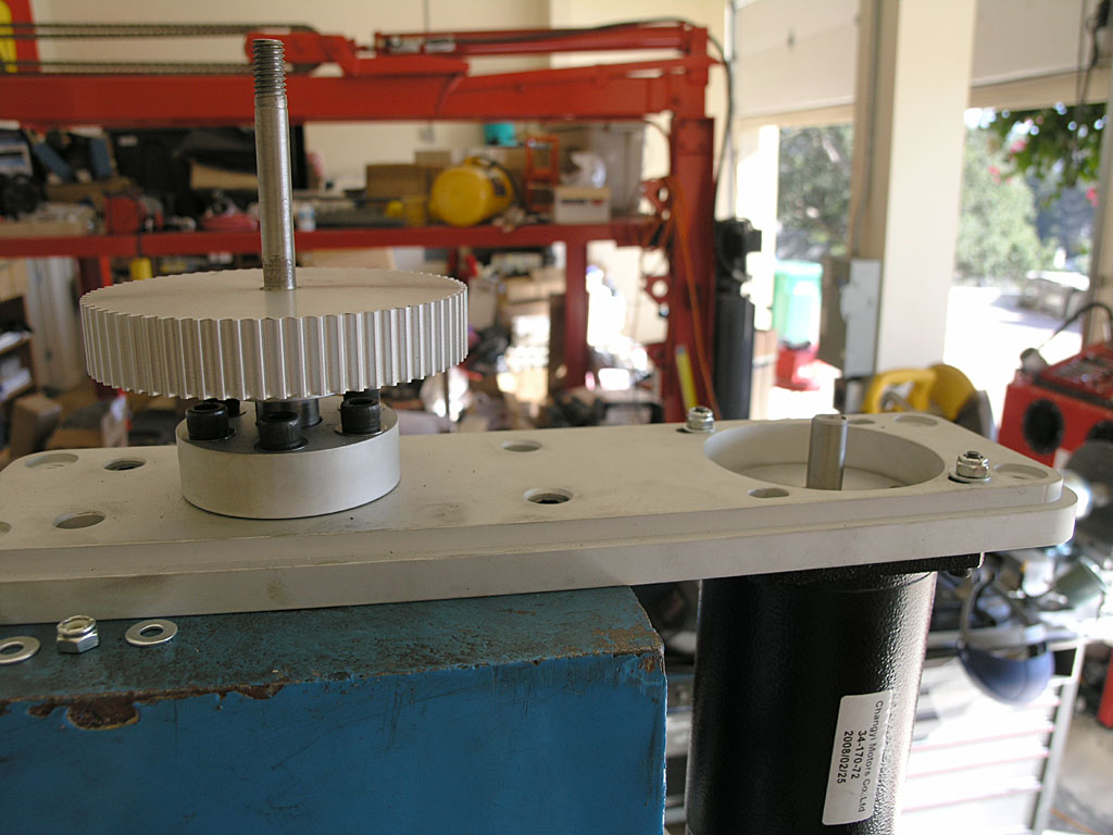 Metal gear or pulley on blue metal base in industrial setting.