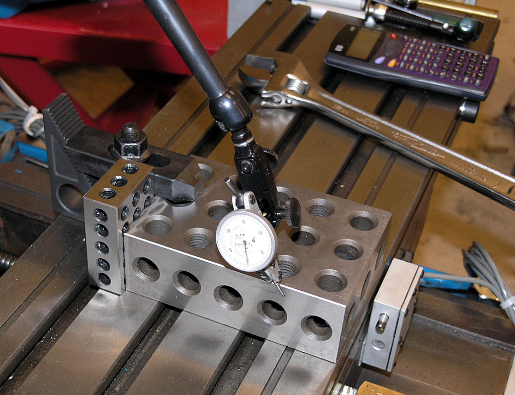 Dark brown metal workbench with vise clamp, caliper, calculator, and other tools.
