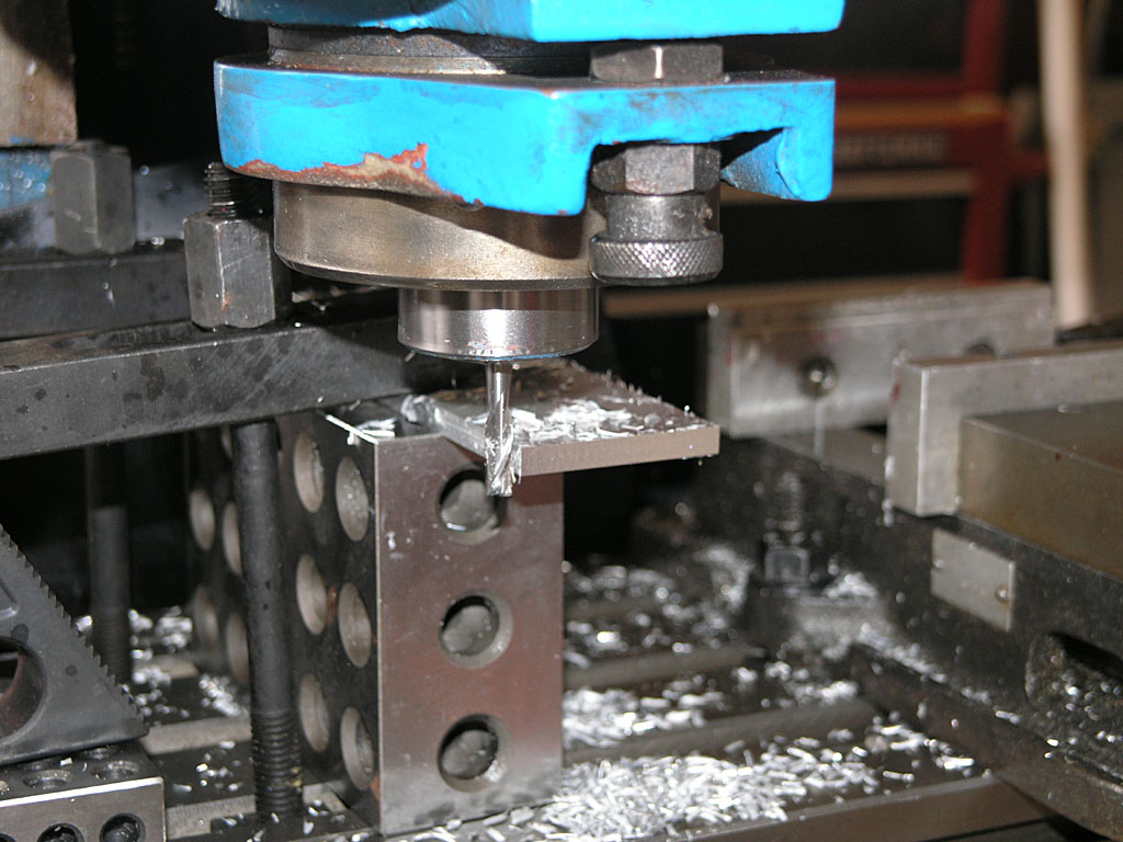 Blue metalworking tool on workbench with metal shavings and machine head.