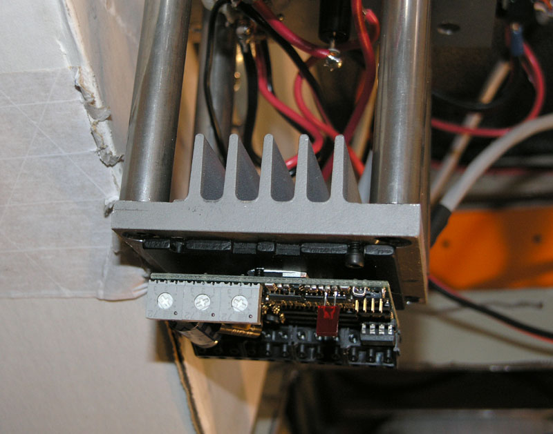 Complex electronic device with gray metal casing and red, black, and white wires.