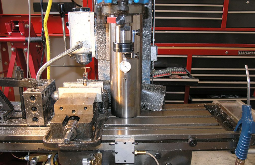 Large metalworking machine with tools and attachments in a garage or workshop setting.