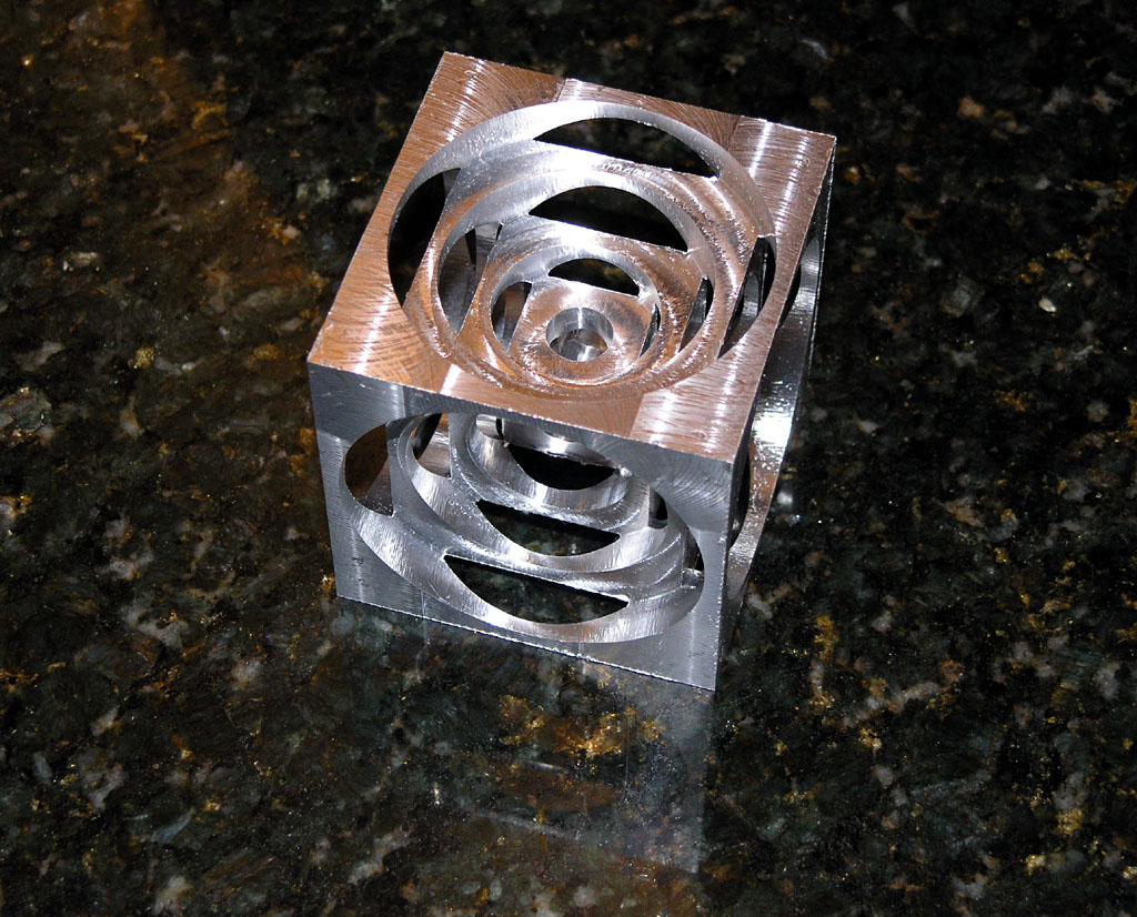 Metal cube with intricate spiral cutouts.