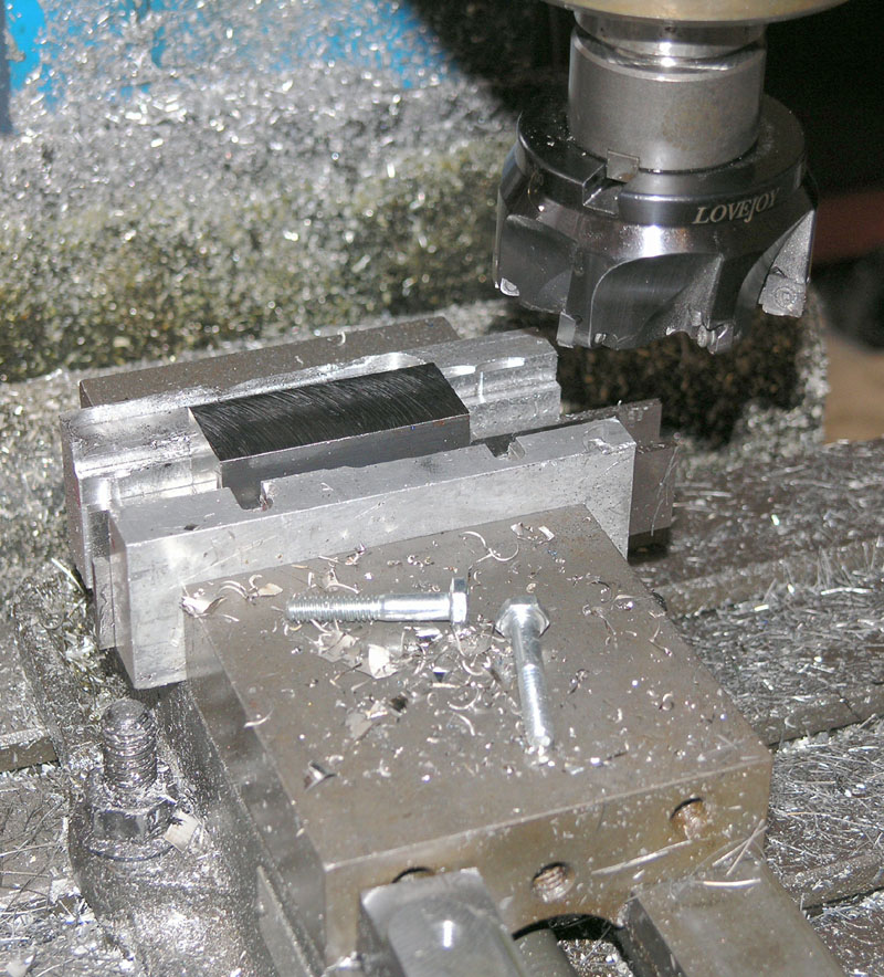 Metalworking machine with Lovejoy coupling and vise, surrounded by metal shavings and scraps.