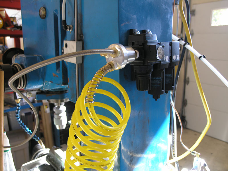 Industrial setup with blue metal component and yellow coiled tubing in a workshop.