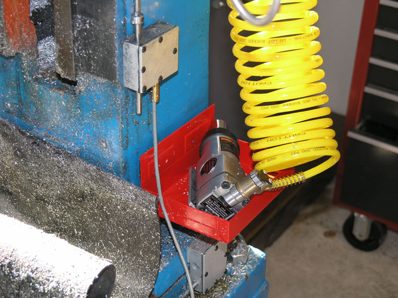 Red plastic holder attached to blue machine, securing silver motor.