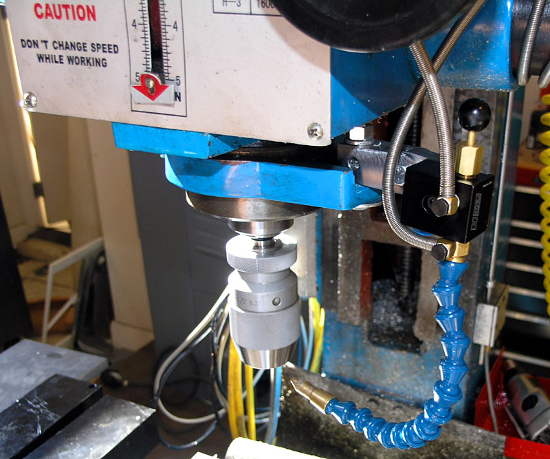 Blue and white drill press with metal column and side dials.