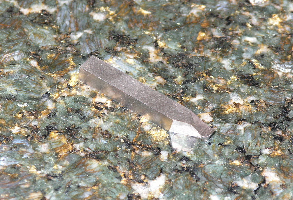 Crystal embedded in rock or mineral surface.