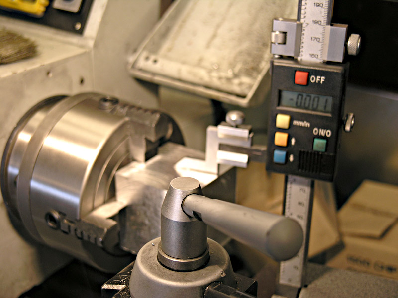 A metalworking lathe with digital readout gauge and large cylindrical component.