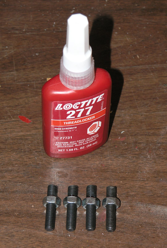 Red Loctite 277 threadlocker bottle with four black bolts on a wooden surface.