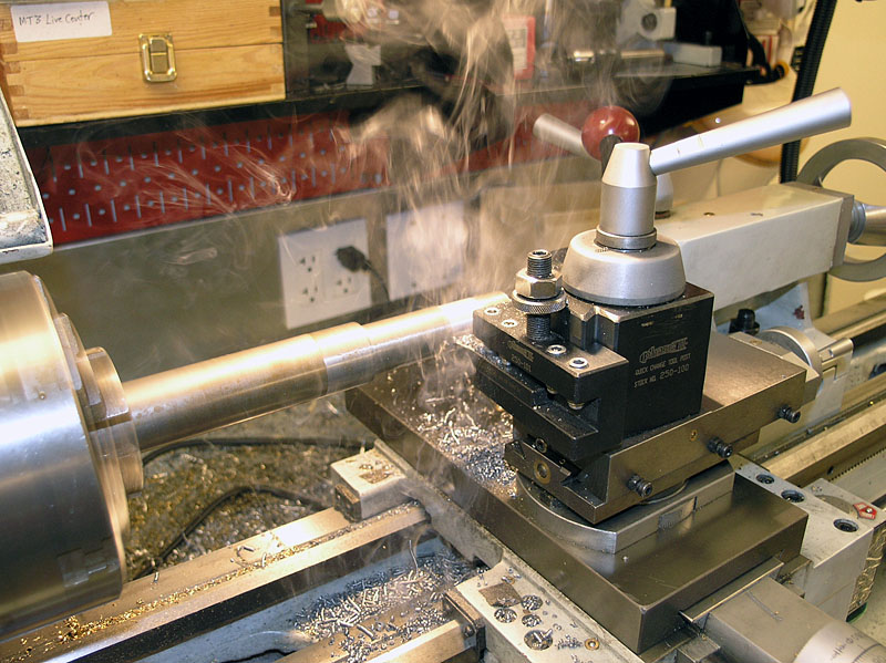 A lathe machine in operation, machining a cylindrical object in a well-organized workshop.