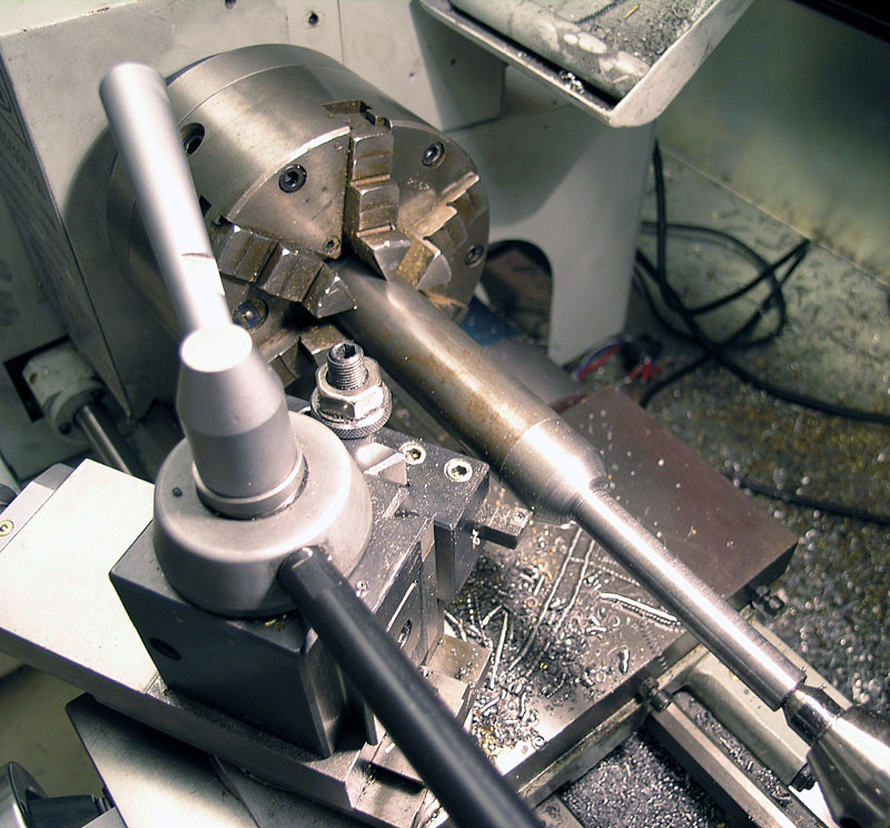 Industrial lathe with metal base and two parallel bars, holding a partially inserted cylindrical workpiece.