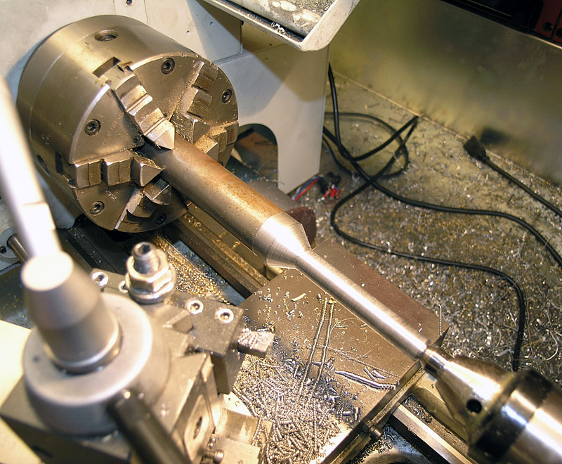 A lathe in a machine shop, showing detailed machinery and metal shavings on the floor.
