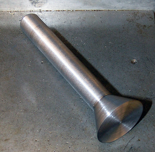 Metal object on gray surface, likely machined metal in a workshop.