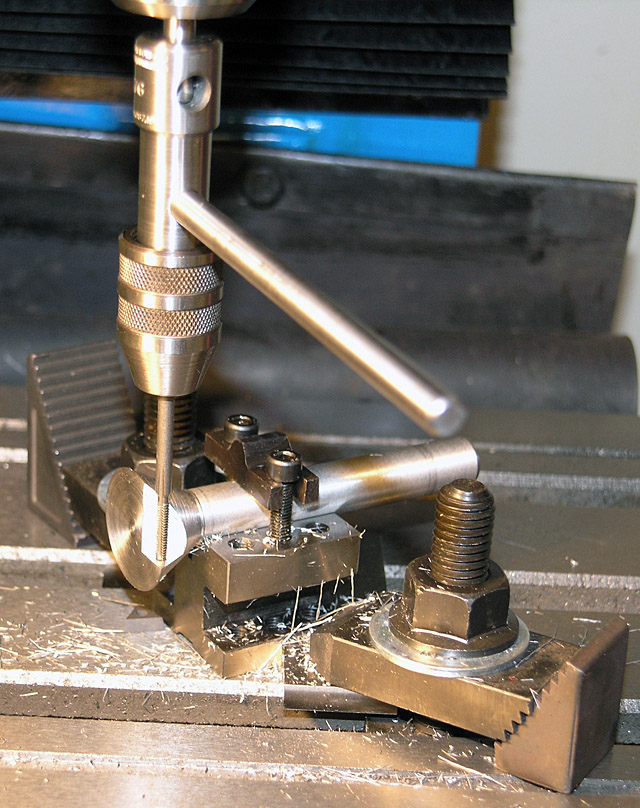 A stainless steel drill press showcased among machinery in a machine shop workshop.