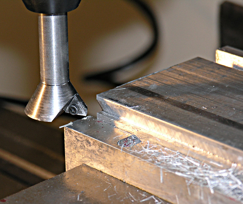 Metal cutting tool positioned over metal in workshop setting.